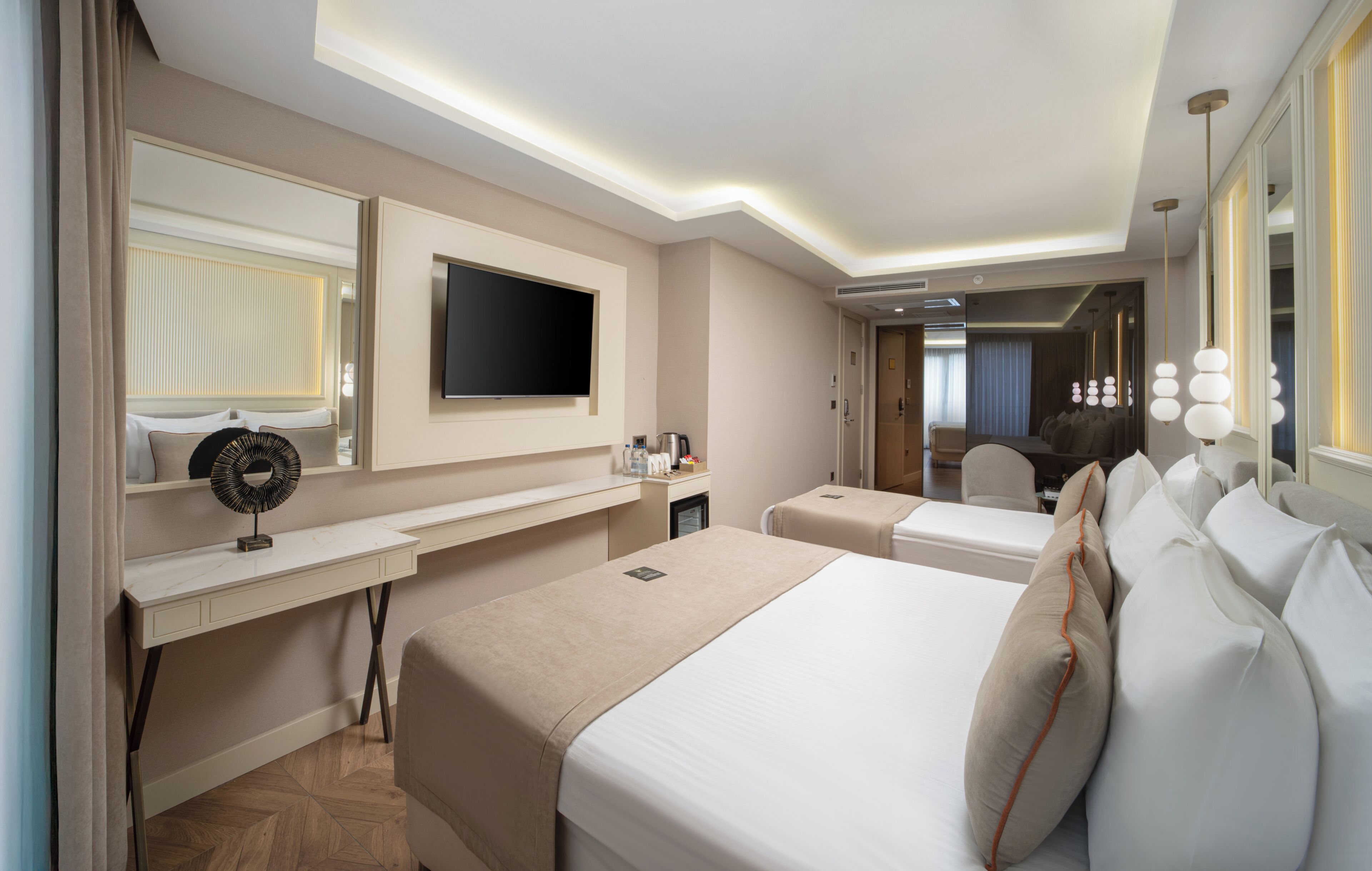 A hotel room with a bed, bedside tables, a TV, a desk, and a mirror.