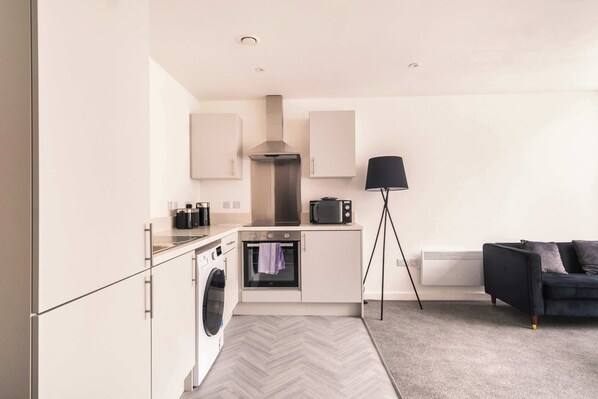 A compact kitchen with a microwave, oven, and washing machine.