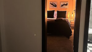 A hotel room with a bed, a nightstand, a lamp, and a sign that reads "HAPPY HOUR". - Close to Leeds Centre - The Snug Apartment (Leeds)
