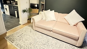 A living room with a beige sofa, a large mirror, and a patterned rug. - Close to Leeds Centre - The Snug Apartment (Leeds)