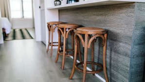 A kitchen with wooden stools, a white countertop, and a grey backsplash. - Cozy 1BR Home by MHM Luxury Properties (Athens)