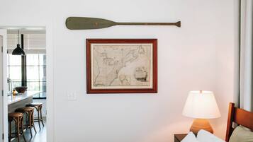 Et værelse med en træseng, et indrammet kort på væggen, en træpagaj og en lampe.