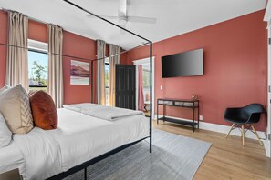 Un dormitorio moderno con cama con dosel, televisor de pantalla plana y escritorio.
