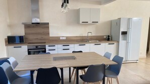 A modern kitchen with a wooden table, black chairs, a microwave, a sink, and a refrigerator. - Gîte au Cœur du Beaujolais, Dans un Domaine Viticole (buuly)