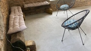 A stone-walled room with a bench, two wire-framed chairs, and a dartboard on the wall. - Gîte au Cœur du Beaujolais, Dans un Domaine Viticole (buuly)