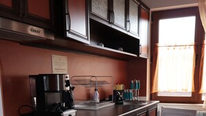 A kitchen with a stove, oven, refrigerator, and a window with curtains.