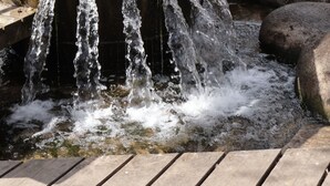 A wooden water feature with cascading water, surrounded by rocks and trees.