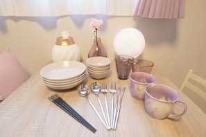A neatly arranged dining table with plates, bowls, cutlery, and a vase with a flower. - Fiore Kinshicho by Tranova (Tokyo)