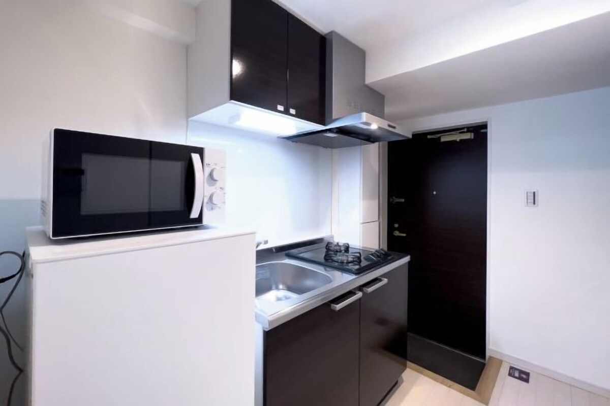 Cozinha moderna com micro-ondas, fogão e armários escuros.