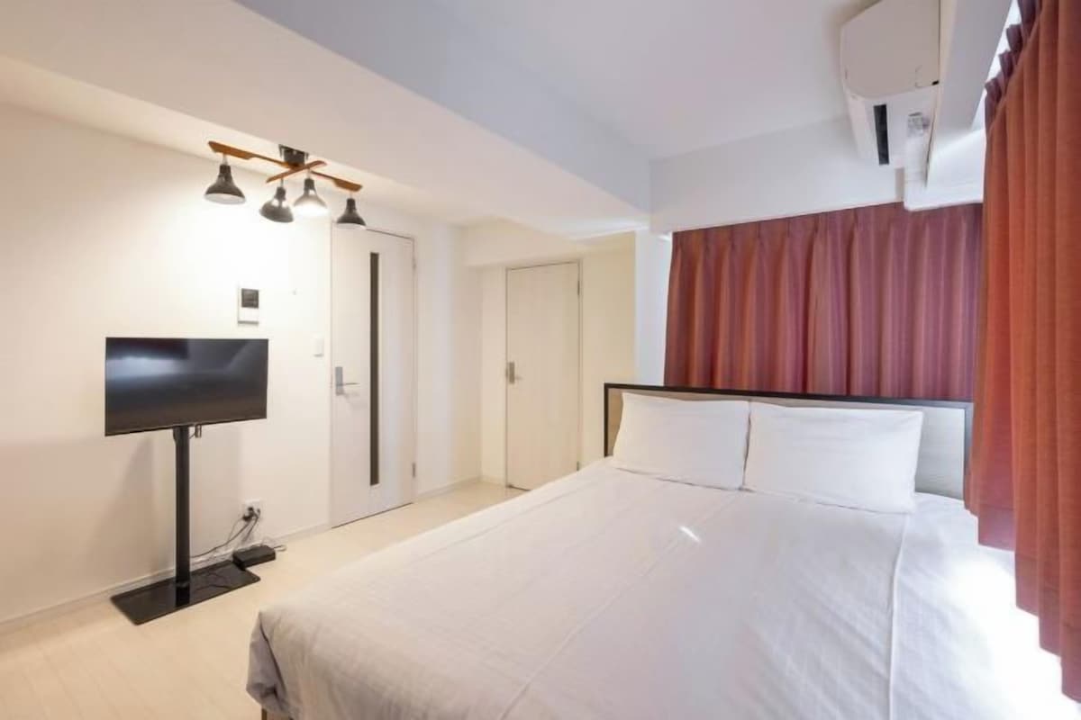 Quarto de hotel com cama, televisão de tela plana, ventoinha no teto e ar condicionado.