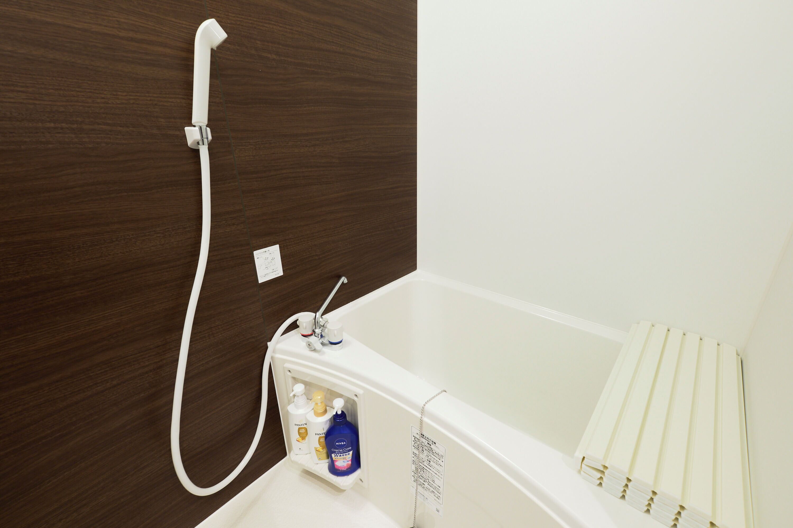 A bathroom with a white bathtub, a shower head, and a towel rack.