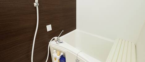 A bathroom with a white bathtub, a shower head, and a towel rack.