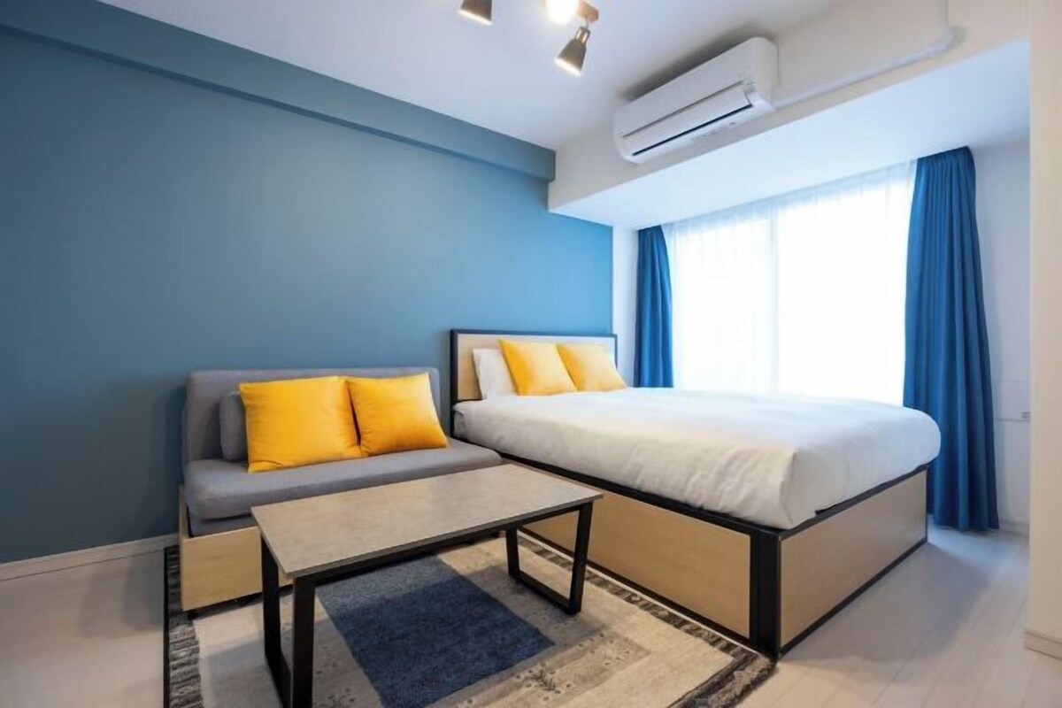 Quarto com cama, sofá, mesa pequena e ar-condicionado.