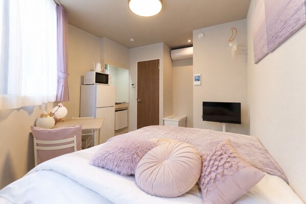 A bedroom with a bed, a desk, a television, and a kitchenette. - Fiore Kinshicho by Tranova (Tokyo)