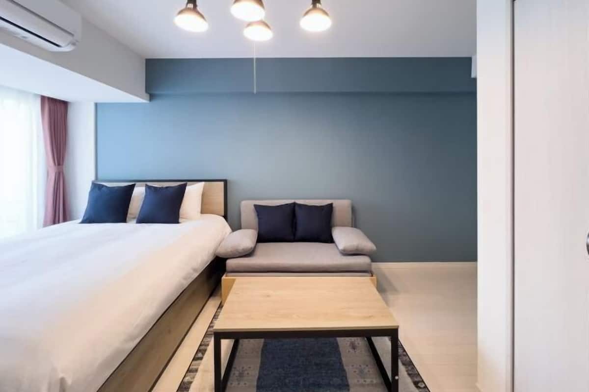A modern hotel room with a bed, sofa, and a small table.