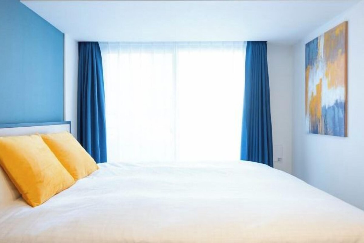 Quarto de hotel com cama, cortinas azuis e um quadro na parede.