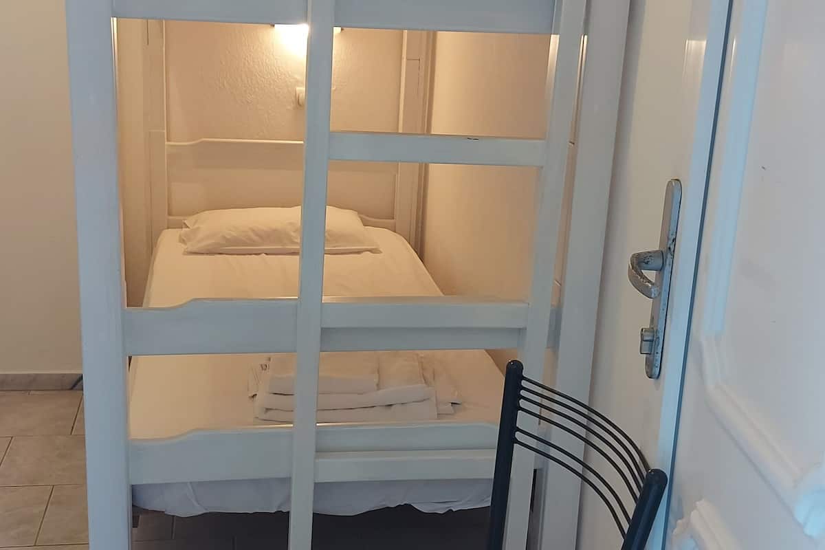 Un lit superposé avec une échelle, une chaise et une porte dotée d’une poignée.