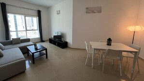 A modern living room with a sofa, TV, dining table, and chairs.