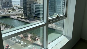 A view from a high-rise window overlooking a cityscape, including a river, palm trees, and modern buildings.