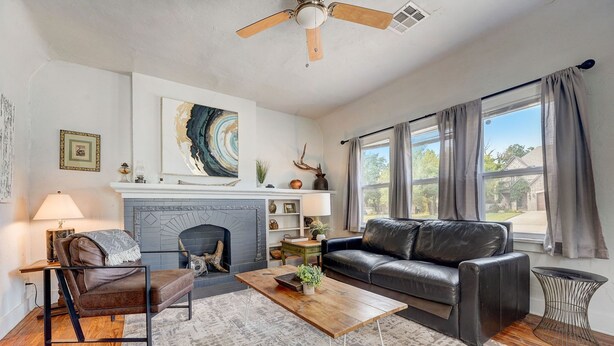 A living room with a fireplace, a sofa, a coffee table, and a ceiling fan. - 2BR Cozy House Near Paseo the Art District (Oklahoma City)