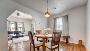 A dining area with a wooden table, chairs, and a hanging light fixture. - 2BR Cozy House Near Paseo the Art District (Oklahoma City)