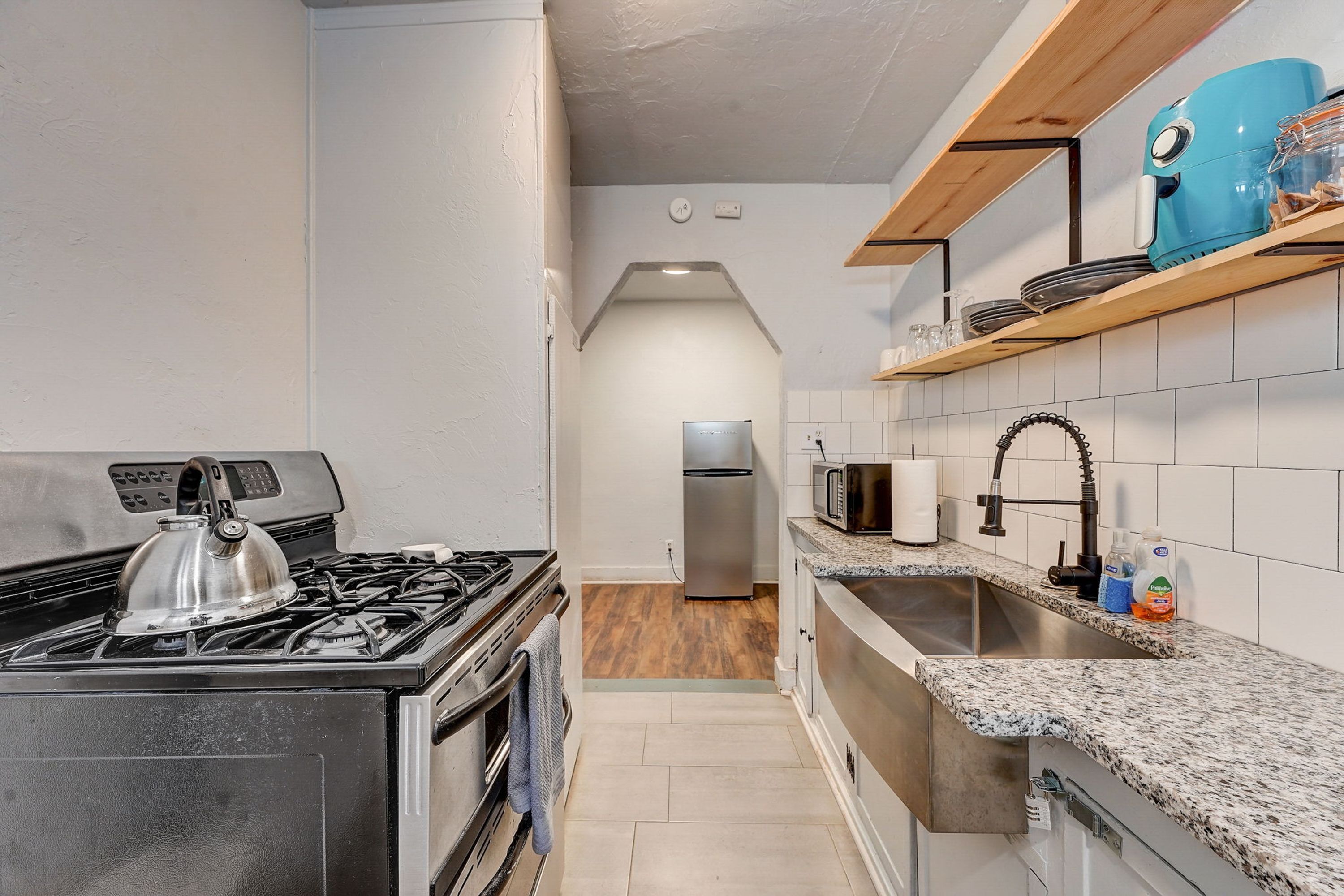 A compact kitchen with a gas stove, oven, microwave, and a stainless steel sink.
