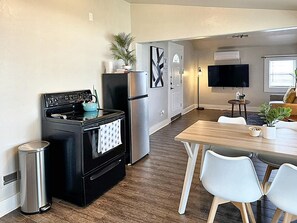 Una cocina moderna con estufa, refrigerador y comedor con sillas y mesa.