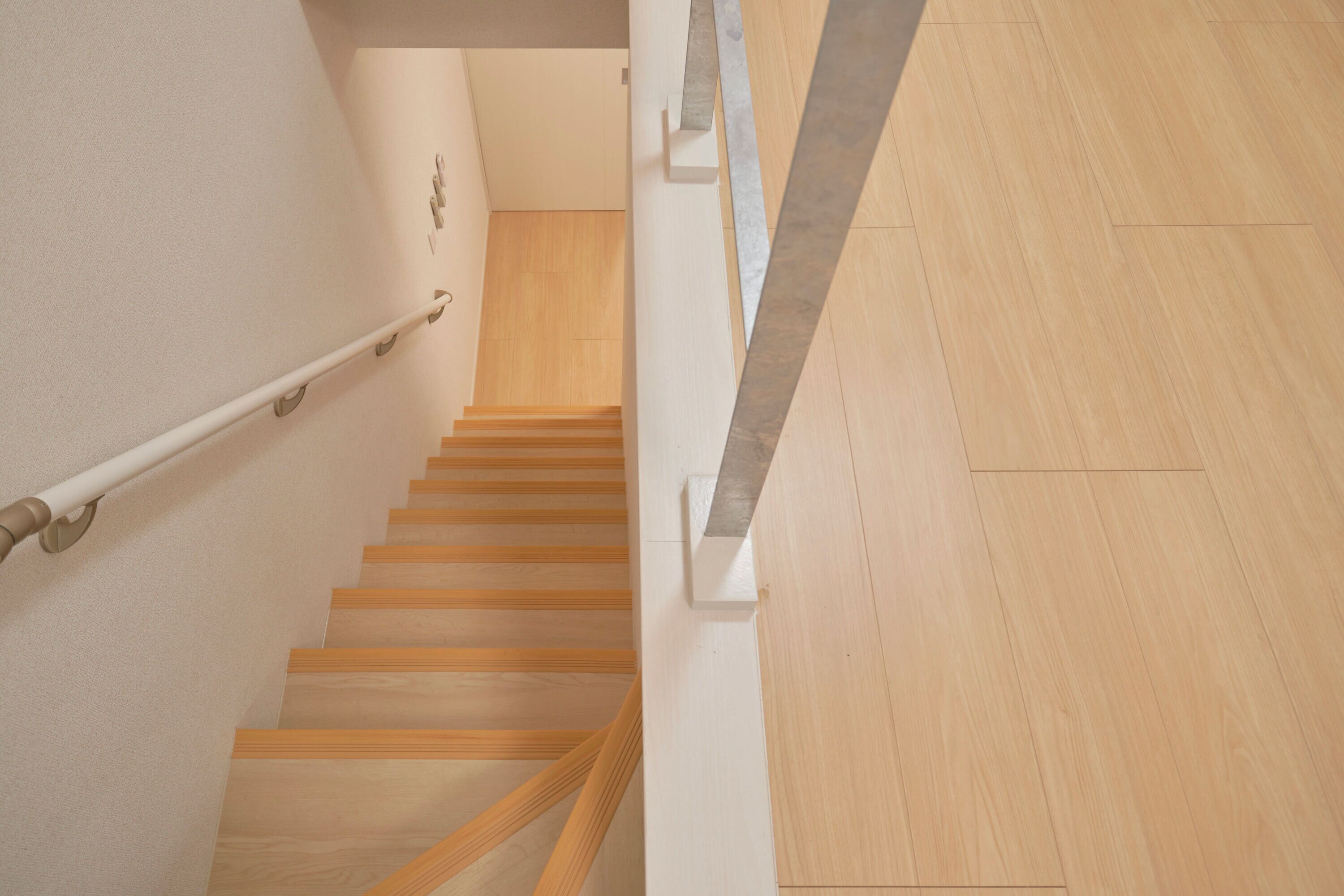 A wooden staircase with a handrail, leading to a landing with a wooden floor.