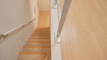 A wooden staircase with a handrail, leading to a landing with a wooden floor.