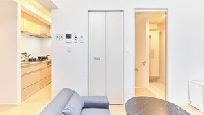 Moderni keittiö, jossa on integroidut kodinkoneet, harmaa sohva ja musta marmoripöytä.