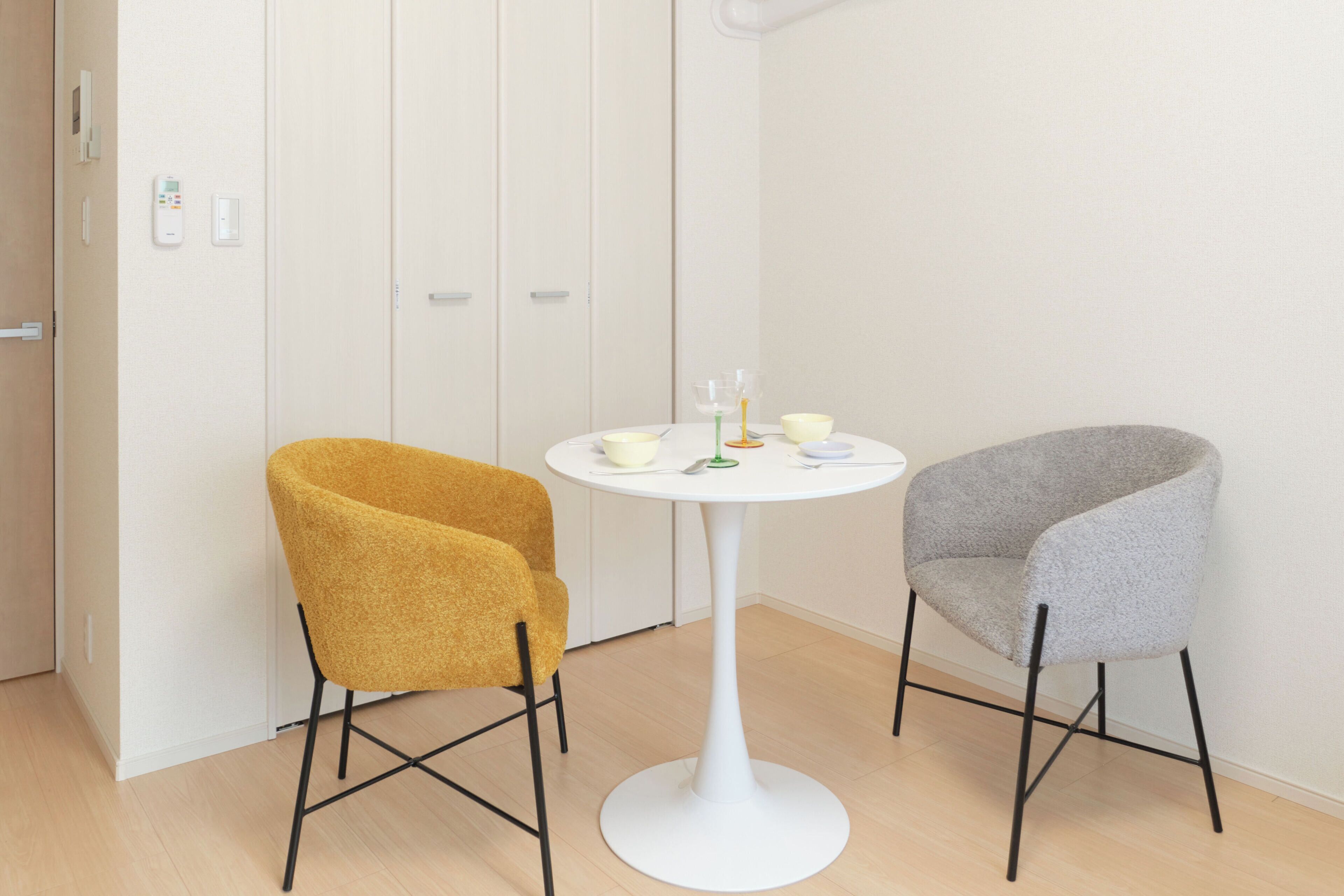 Two chairs and a small table in a room with a white door and light-colored walls.