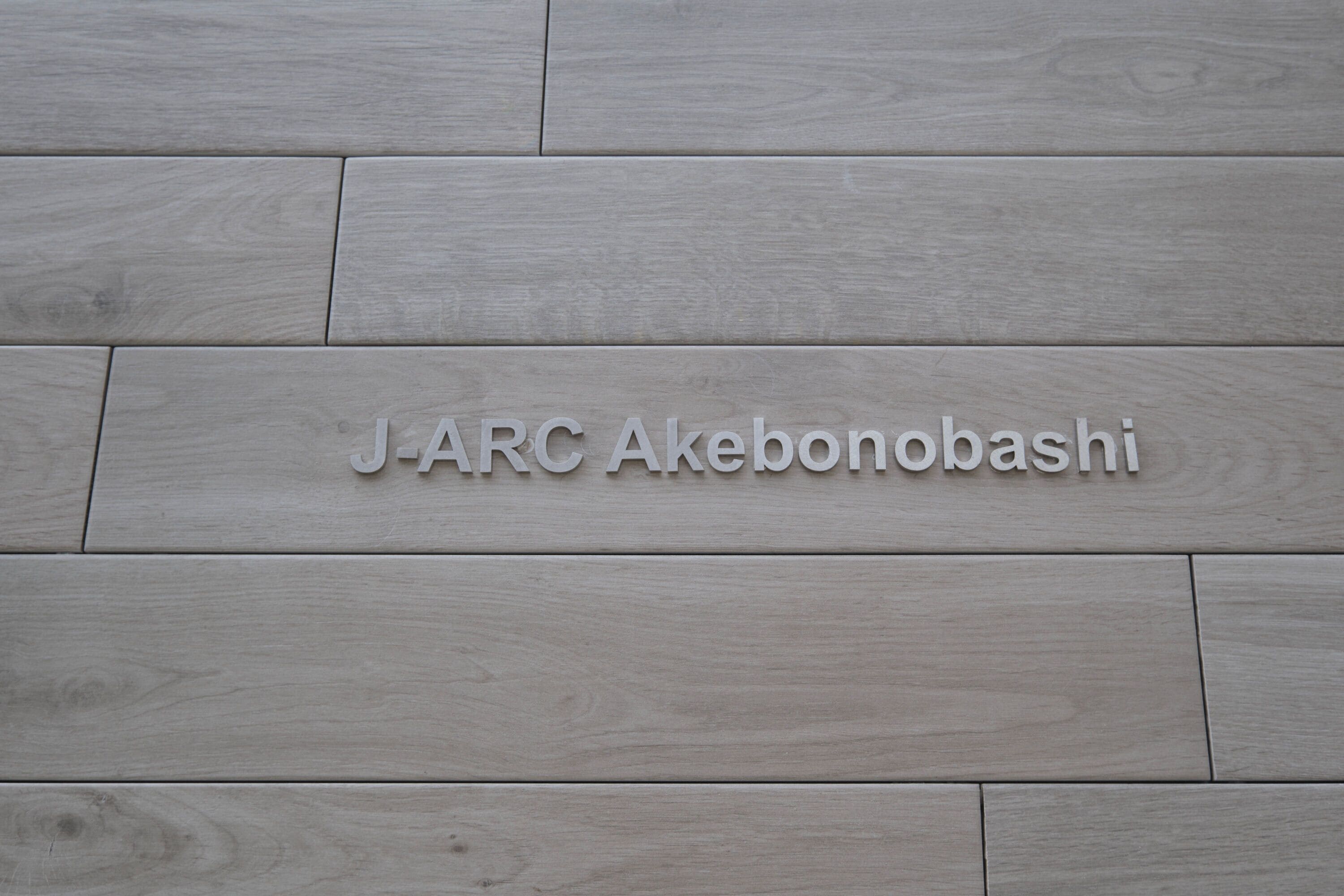 A wooden floor with the text "J-ARC Akebonobashi" engraved on it.