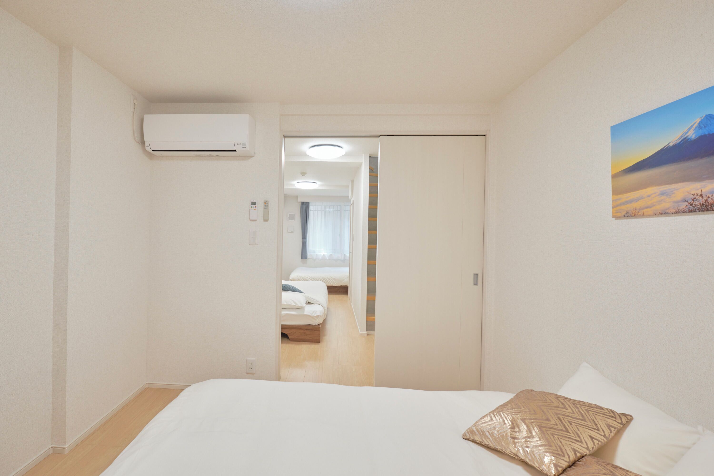 Una habitación de hotel con una cama, un cuadro en la pared y un equipo de aire acondicionado.