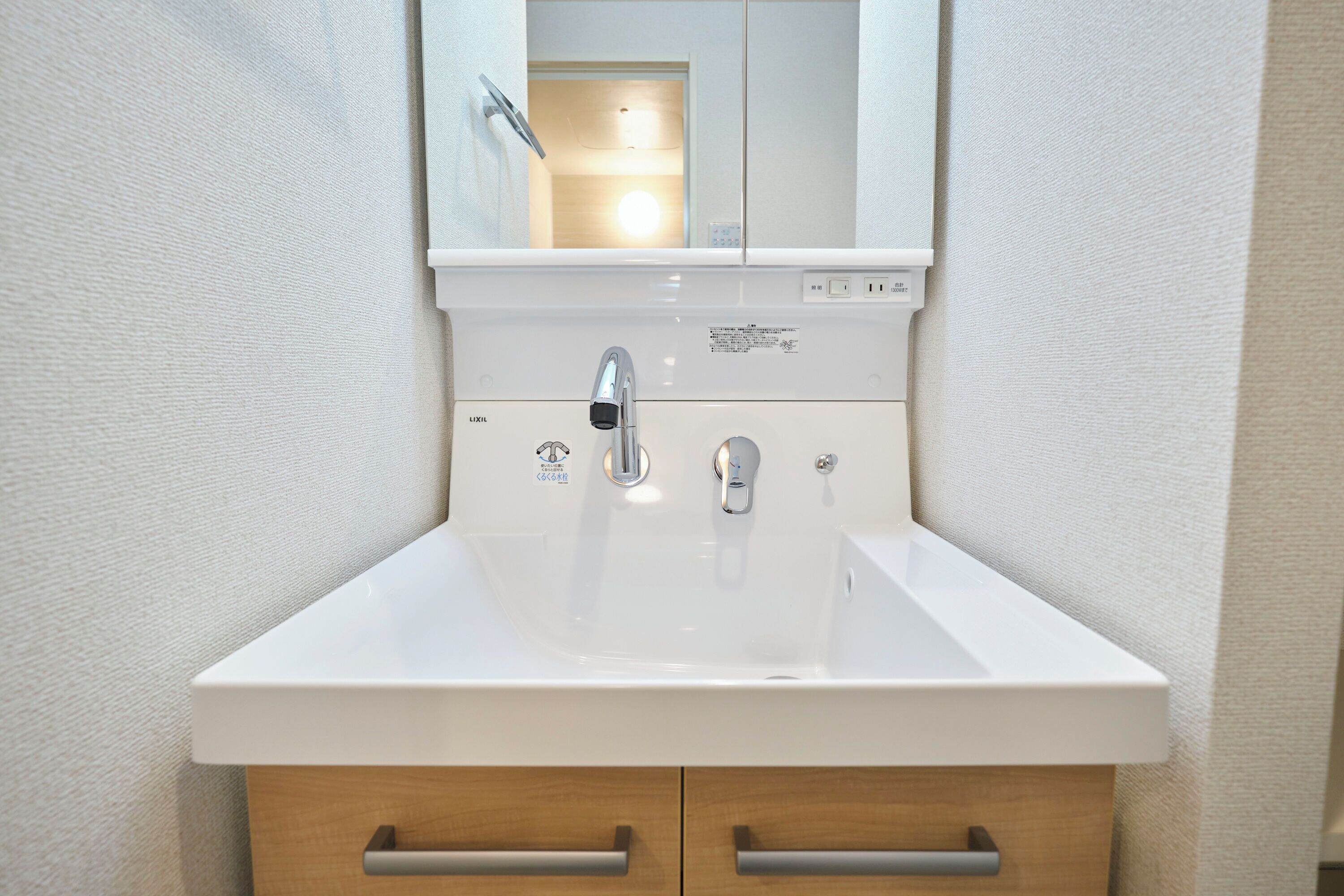 A white bathroom sink with a mirror above it, a faucet, and two wooden cabinets below.