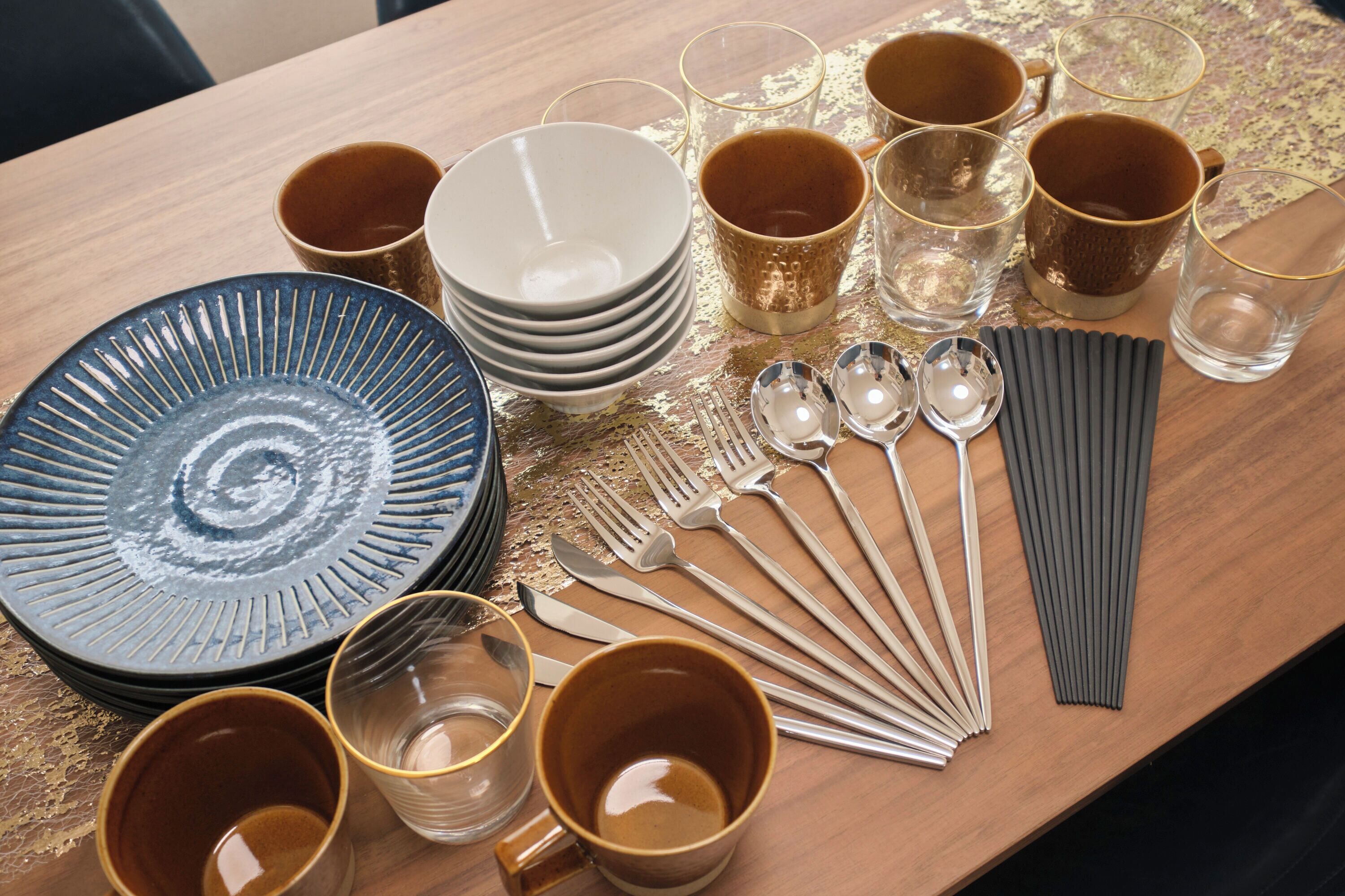Una mesa con varios elementos de vajilla, como platos, tazones, tazas y cubiertos.