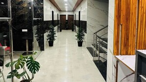 A clean, modern hallway with a marble floor, wooden paneling on the walls, and potted plants. - Panchavati Resto and Spa (Mahabaleshwar)