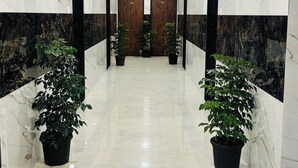 A hallway with marble walls, wooden ceiling beams, and potted plants. - Panchavati Resto and Spa (Mahabaleshwar)