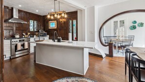 Una cocina moderna con una isla central, armarios de madera y un comedor con una mesa redonda y sillas.