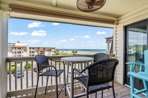 A balcony with two wicker chairs and a small table, overlooking a beach and buildings. - Ocean Forest Villas Unit D304 - Ocean view (Myrtle Beach)