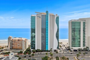 Un hotel moderno con una fachada curva distintiva, varios pisos y vistas a la playa.
