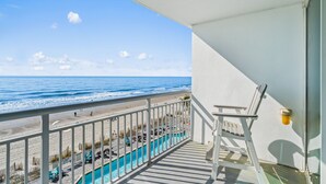 Un balcon avec vue sur l’océan, une piscine et une plage.