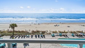 Une vue sur la plage avec une piscine et des chaises longues.