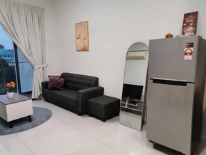 A modern living room with a black sofa, a small side table, a mirror, and a refrigerator. - Cityview 2BR Country Garden Danga Bay @ Natol (Johor Bahru)