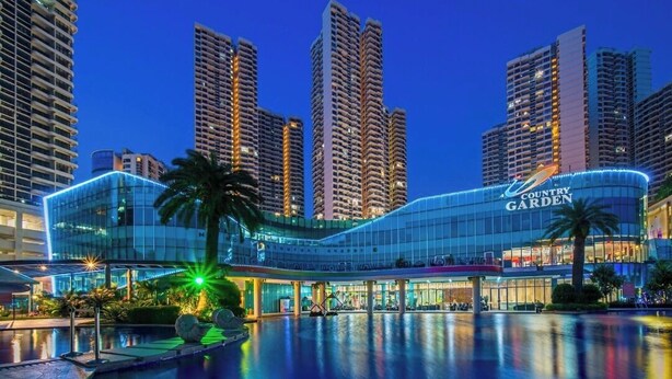 A modern hotel with a curved facade, a pool area, and high-rise buildings in the background. - Cityview 2BR Country Garden Danga Bay @ Natol (Johor Bahru)