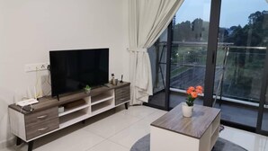 A modern living room with a flat-screen TV, a wooden coffee table, and a balcony with a view of the city. - Cityview 2BR Country Garden Danga Bay @ Natol (Johor Bahru)