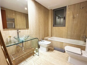 Et moderne badeværelse med vask i glas, toilet, bidet og badekar.
