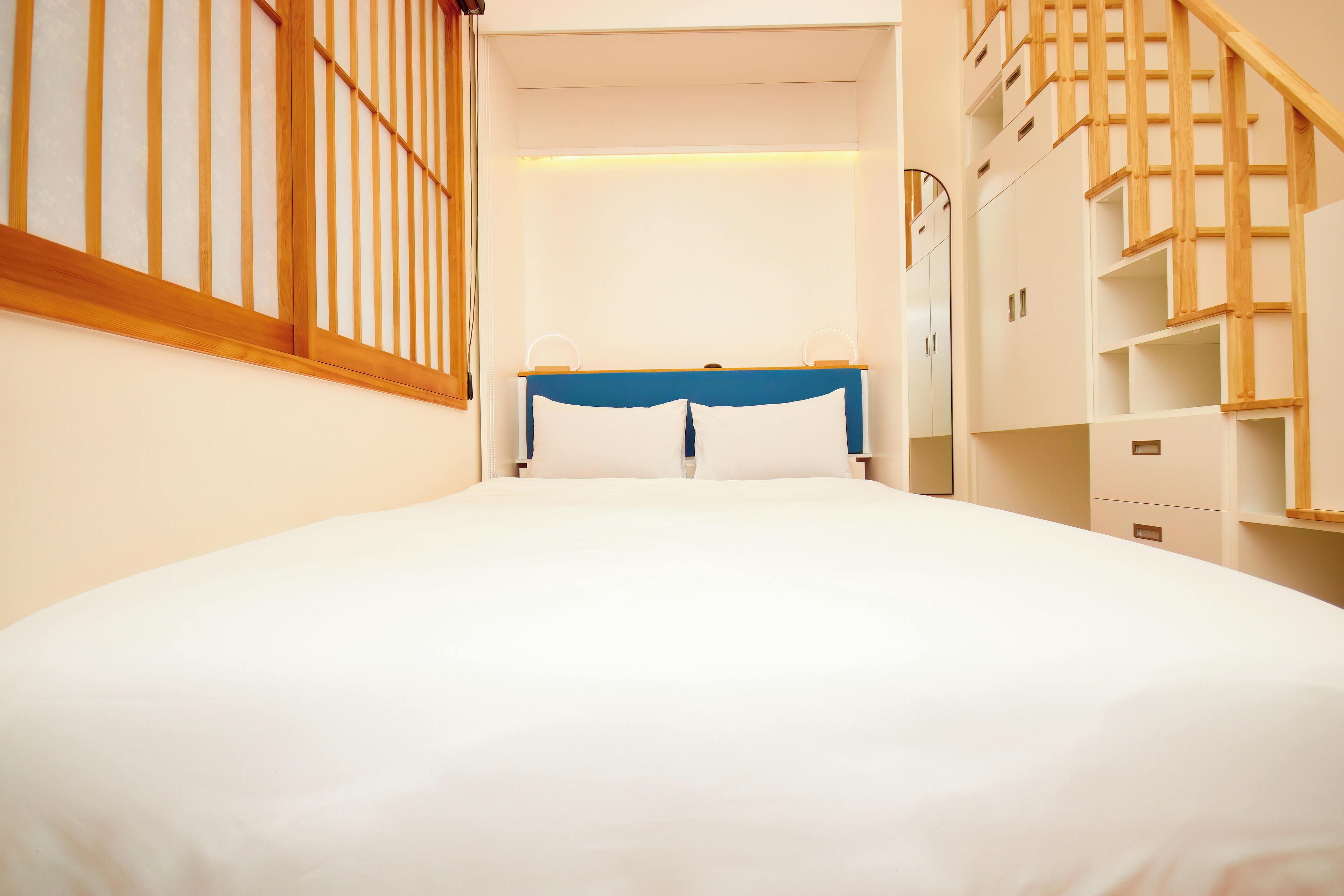 A bedroom with a bed, a wooden headboard, a wardrobe, and a staircase.