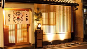 A traditional Japanese building with a tiled roof, a wooden door with a sliding panel, and a small clock on the wall. - Asakusa Ryokan Vacation Rental Tokyokoso (Tokyo)