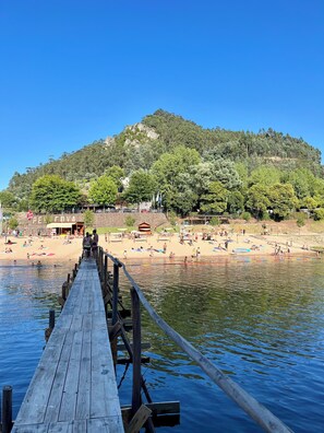 A wooden pier leading to a beach with people swimming and sunbathing. - Design village house near River Beaches and Coimbra (Coiço)