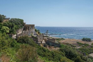 A coastal historical site with stone buildings, a pathway, and a view of the sea.